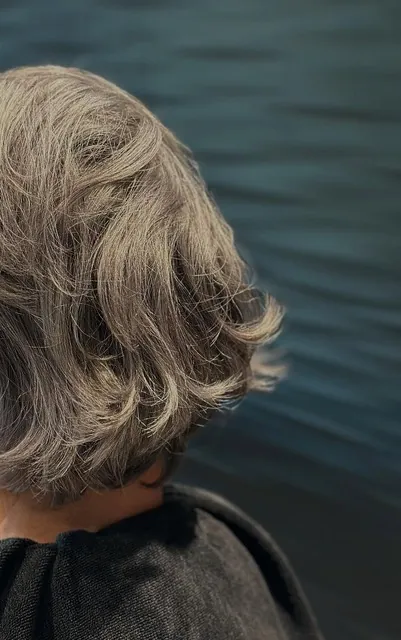 Coupe courte ondulée vue de dos, devant le mur à vagues du salon Gem Coiffure à Borgo
